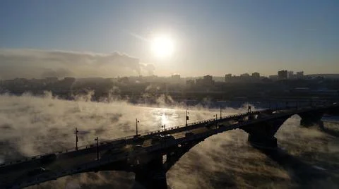 The old bridge over the Angara river. Steam is emitted from the water Stock Photos