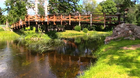 Old bridge over fast flowing river and girl in suuny day park Stock Footage 41539597