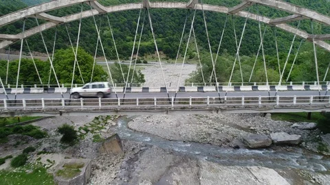 On the old bridge over a mountain river passes a white car. Aerial view. Stock Footage 91159069