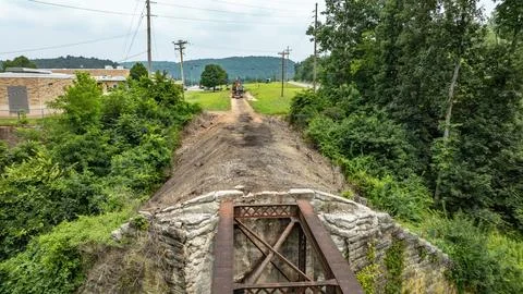 Old Bridge Structure Near a Cleared Area With Machinery in the Background a.. Stock Photos