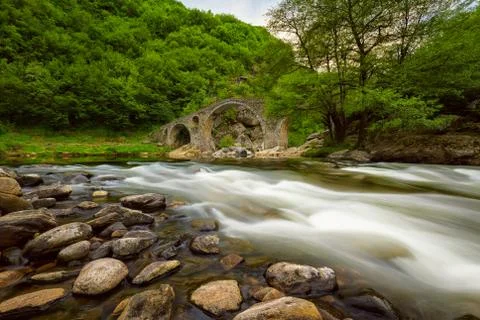 Old bridge through river with fast stream Stock Photos