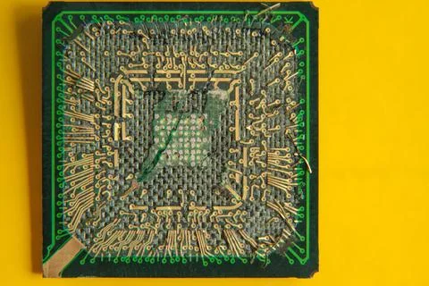 An old broken computer CPU with a torn chip on a yellow background Stock Photos