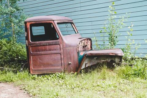 Old broken down abandoned rusted truck sits in a overgrown patch of weeds Stock Photos