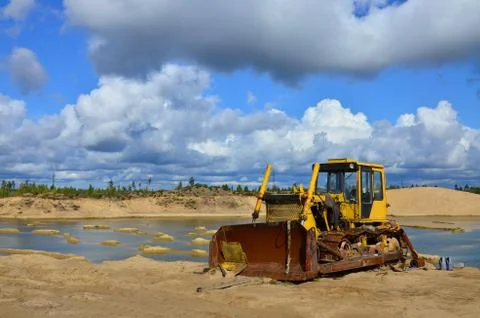 An old broken-down rusty crawler tractor lives out its last days, sand quarry Stock Photos