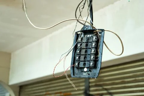 Old broken electricity junction box hanging on wires Stock Photos