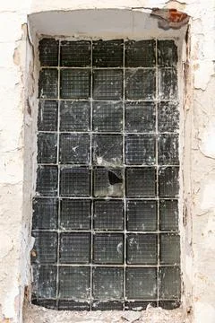 Old broken glass block window in a weathered white concrete wall of an aban Stock Photos