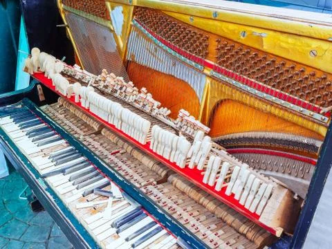 An old broken piano with a missing wall and cover and broken keys Stock Photos