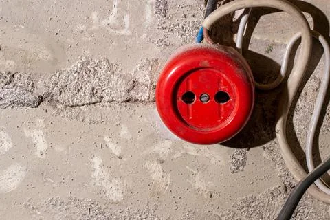 An old broken red electrical outlet on a brick wall with wires. Stock Photos