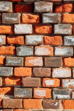 An old broken wall of gray orange bricks Stock Photos