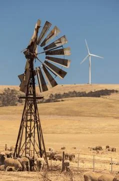 Old broken wind pump and new wind generators distorted by hot air. south aust Stock Photos