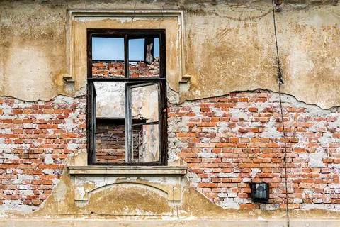 An old broken window in the chipped wall of the building to be demolished. 스톡 사진