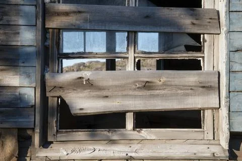 Old broken window covered with boards of destroyed and abandoned house Stock Photos
