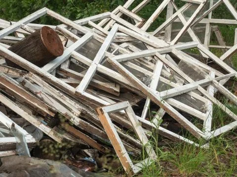 An old broken window frames piled together on green grass. A lot of wooden Foto stock