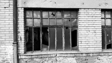 Old broken windows on an abandoned old building. Symbol of economic depressio Stock Photos