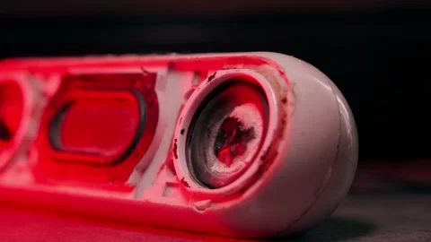 An old broken wireless speaker plays bass close-up in red lighting. The bent Stock Footage 208403416
