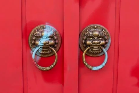Old bronze door knobs with the shape of a lion's head on red door Fotos de archivo