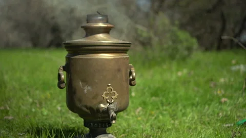An old bronze samovar stands on the grass at a picnic. Stock Footage 195046006