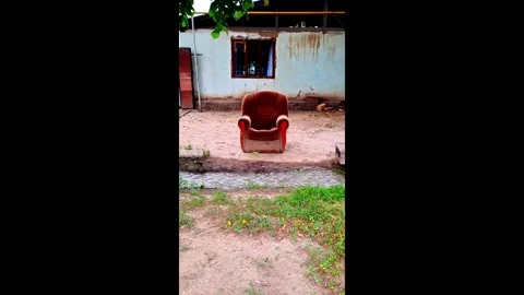Old Brown Armchair in Front of Weathered House Wall Stock Footage 314760981