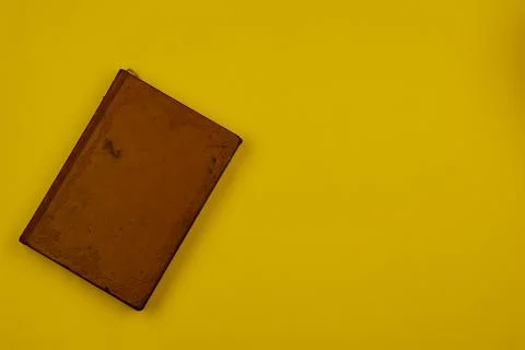 Old brown leather-bound diary with a yellow background. Stock Photos