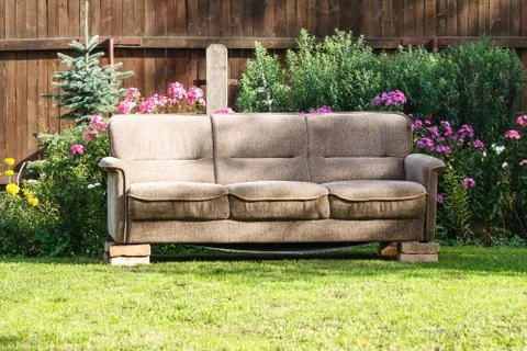 Old brown sofa with broken legs outdoors in the garden Foto stock
