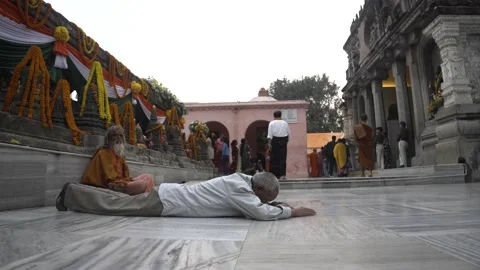 Old buddhist man doing prostrations in front of the Mahabodhi temple Stock Footage 230928249