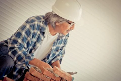 Old Builder craftman is leveling brick wall in vintage tone Stockfoto's