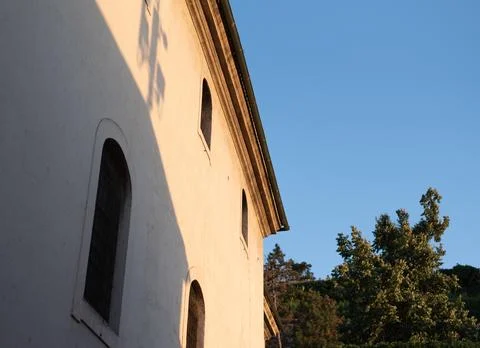 Old building facade with arched windows is bathed in warm sunset light Stock Photos