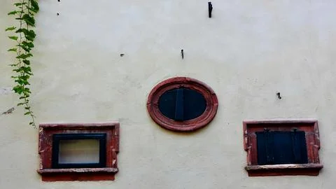 Old Building Facade With Two Windows and a Round Decorative Frame Foto stock