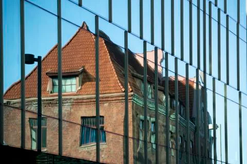 Old building is reflected in the glass surface of the modern building Stock Photos