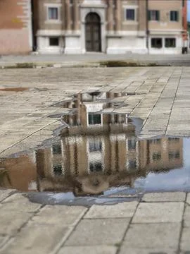 Old buildings in Venice reflected in puddle with defocused foreground and b.. Foto stock