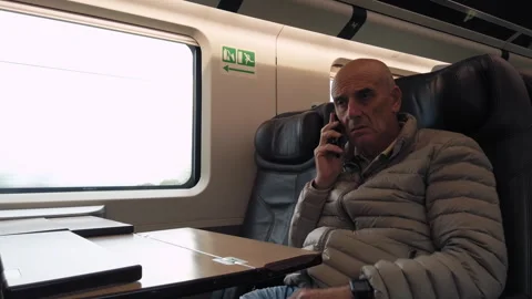 Old businessman making a work call while traveling on an high speed train Stock Footage 254473018