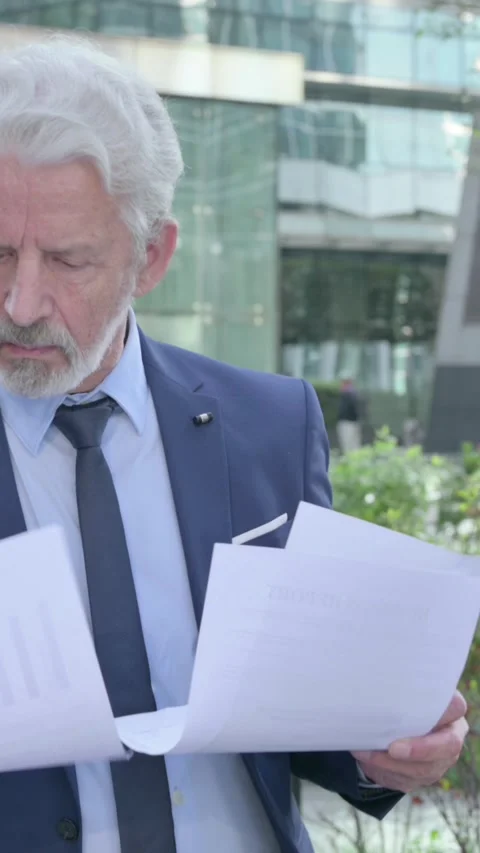 Old Businessman Reading Documents while Walking on the Street, Vertical Video Vídeo Stock 339671198