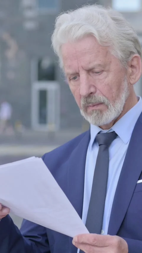 Old Businessman Reading Documents while Standing Outdoor, Vertical Video Vídeo Stock 339672144