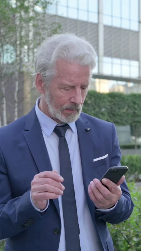 Old Businessman using Smartphone while Walking on the Street, Vertical Video Stock Footage 339670782