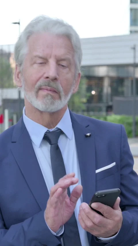 Old Businessman using Smartphone while Walking on the Street, Vertical Video Stock Footage 339670806