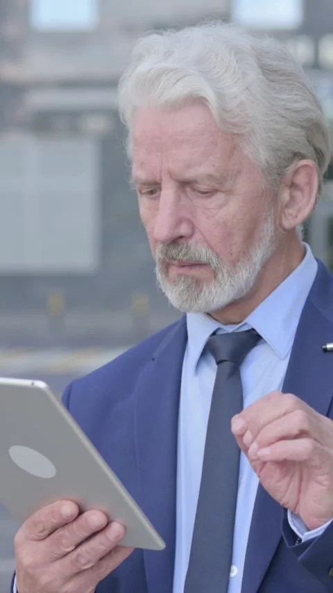 Old Businessman Using Tablet while Standing Outdoor, Vertical Video Vídeo Stock 339672079