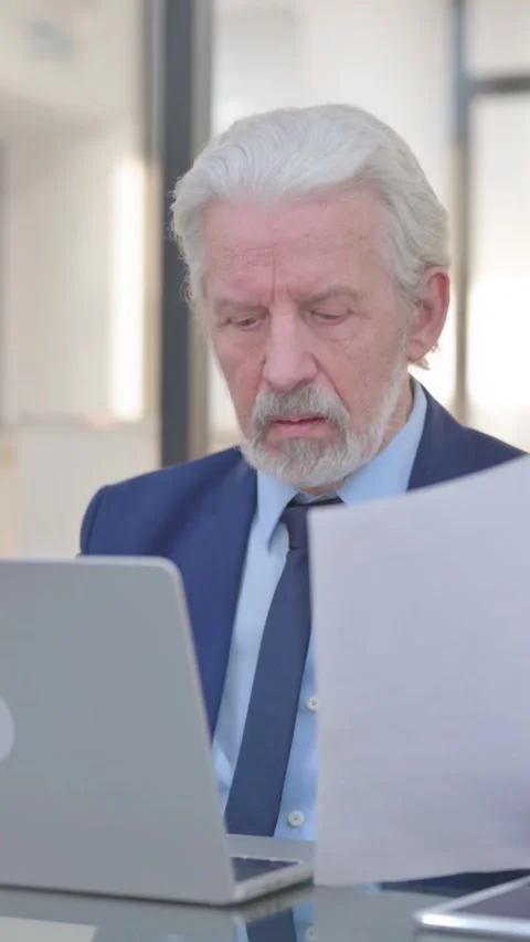 Old Businessman Working on Documents and Laptop, vertical video Video stock 325564844