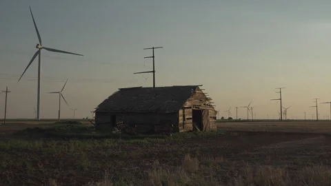 An old cabin set among active wind turbines, 4K. Stock Footage 244879585
