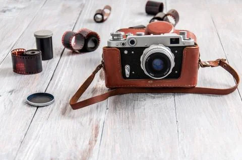 Old camera, bag and films on a gray wooden table. A vintage camera stands on  Stock Photos