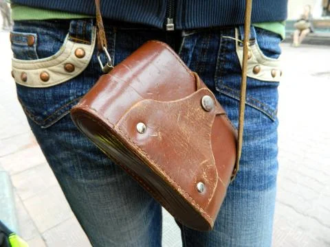 An old camera in a brown case hangs on a belt around his neck Stock Photos