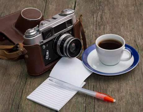 The old camera, coffee and notebook with the handle on a wooden table Stock Photos