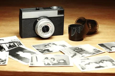 Old camera next to out of focus black and white photographs Stock Photos