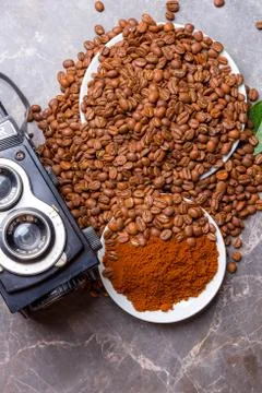 An old camera, roasted coffee beans and ground coffee on a marble table Fotos de archivo
