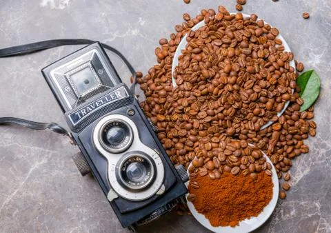 An old camera, roasted coffee beans and ground coffee on a marble table Stock Photos