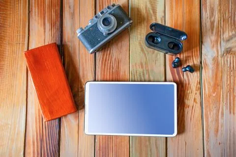 Old camera tablets and wireless headphones are on wooden desktops Foto stock