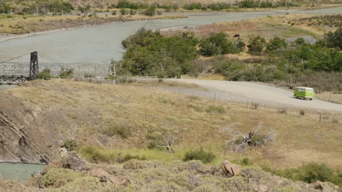 Old campervan driving over a bridge and down a dirtroad in Patagonia Video stock 258424668