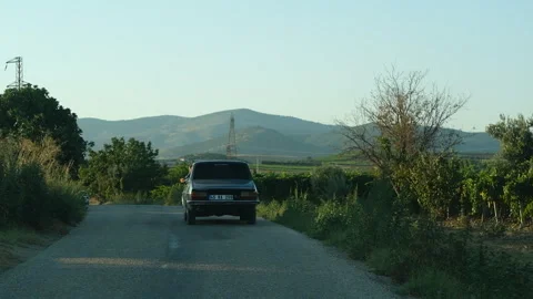 An old car drives down a winding country road Stock Footage 326108547