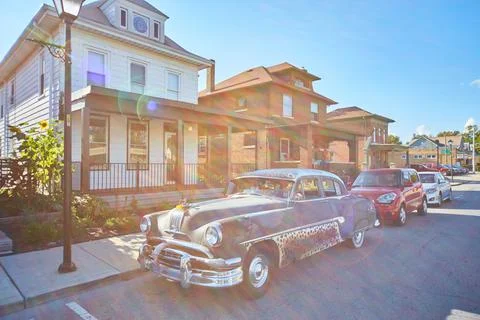 Old car with leopard print in front of an old white house and a streetlamp Foto stock