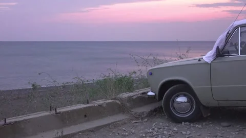 An old car stands on the beach. Sunset Stock Footage 130438957