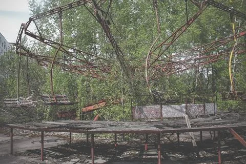 Old carousel in the ghost town of Pripyat. Abandoned city overgrown with trees Stock Photos